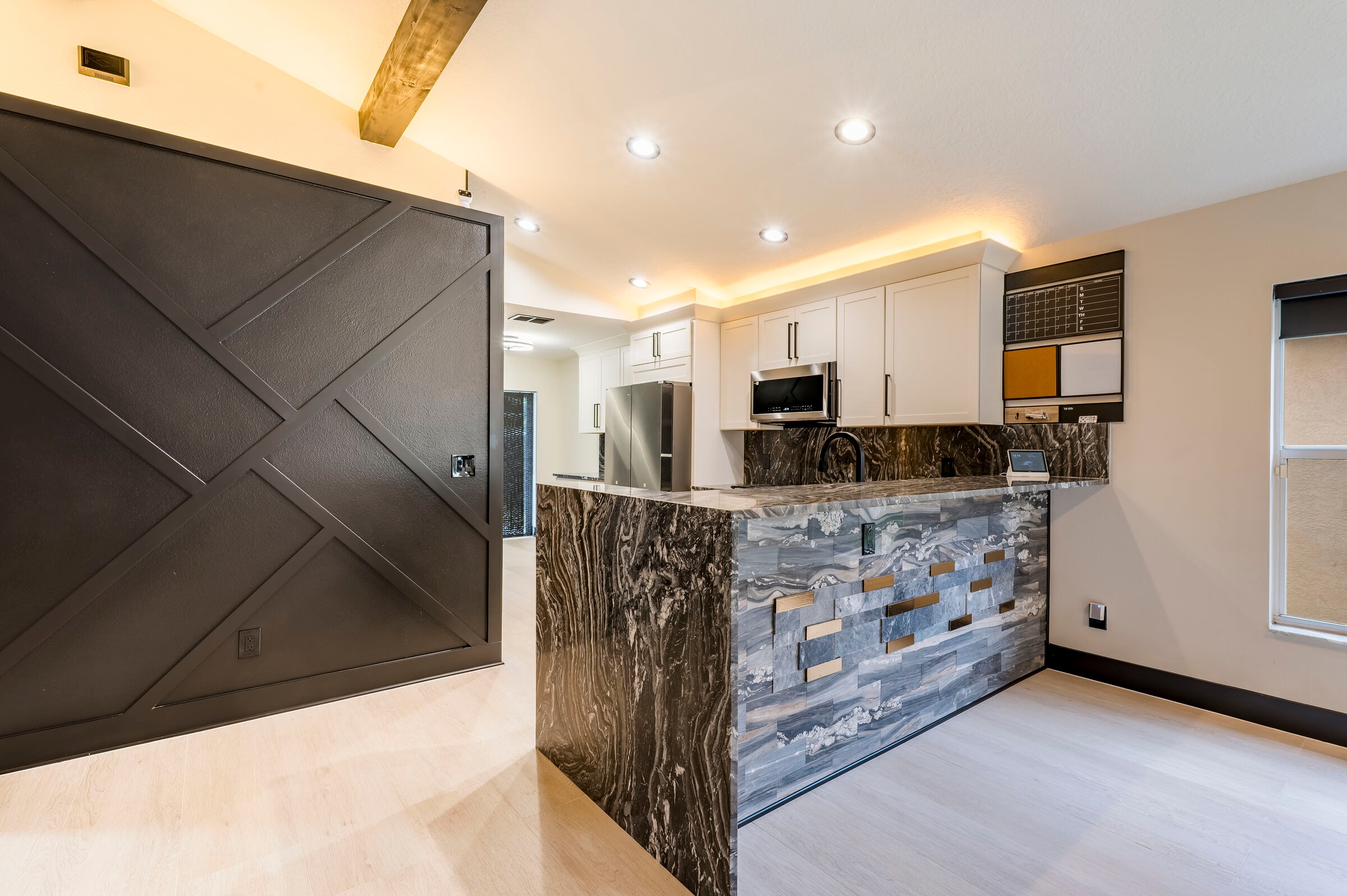 Kitchen island detail at 7522 Oxford Garden Circle in Apollo Beach Florida — stone waterfall edge, geometric barn door, and open great room