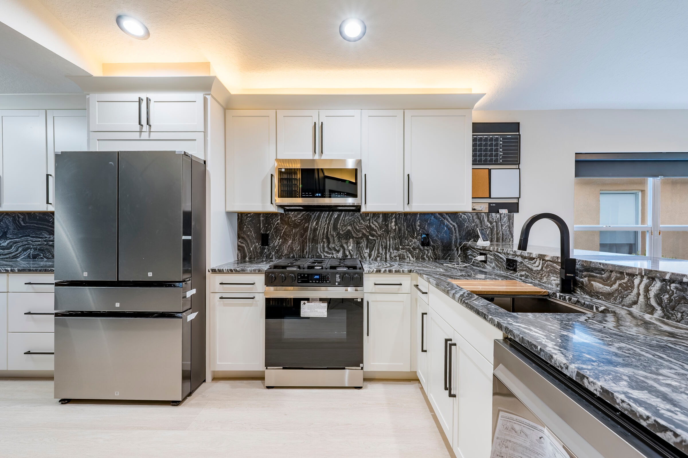 Renovated kitchen at 7522 Oxford Garden Circle Apollo Beach Florida — white shaker cabinets, dark marble backsplash, and stainless steel appliances