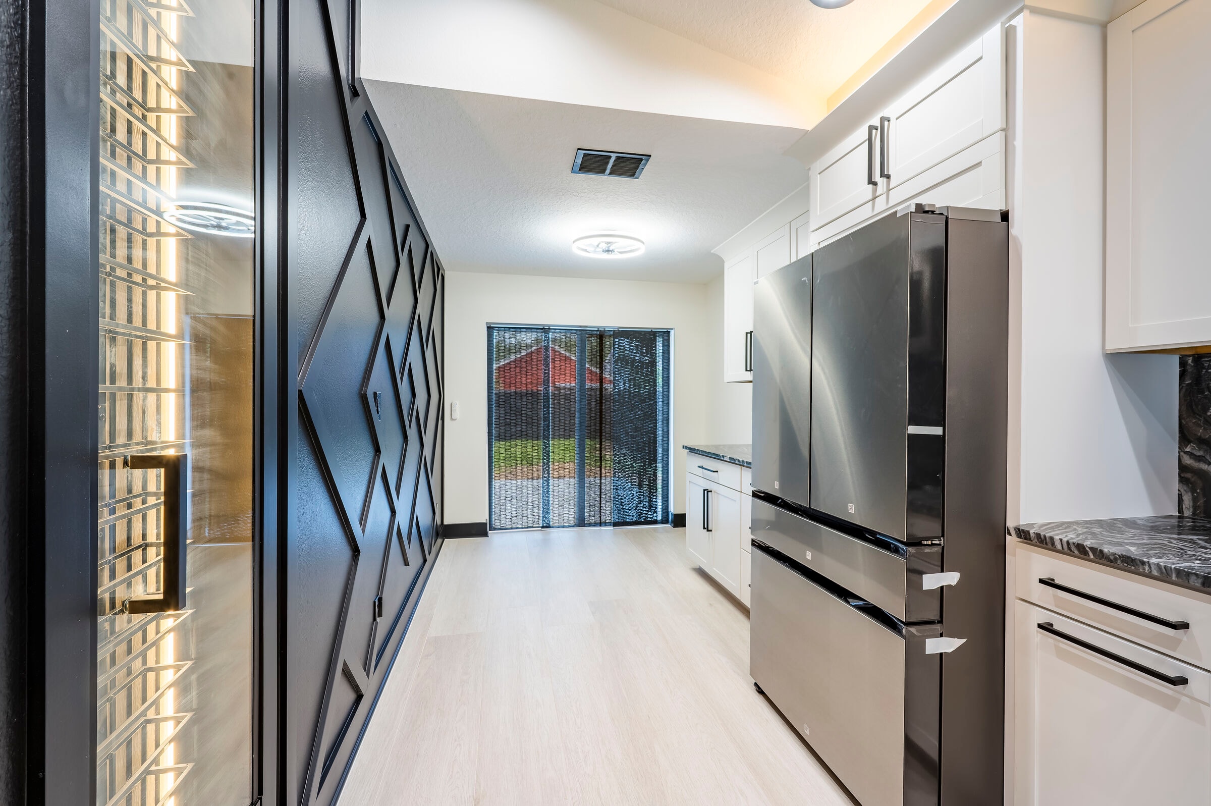 Kitchen at 7522 Oxford Garden Circle Apollo Beach Florida — stainless French-door refrigerator, geometric barn door, and sliding glass door to backyard