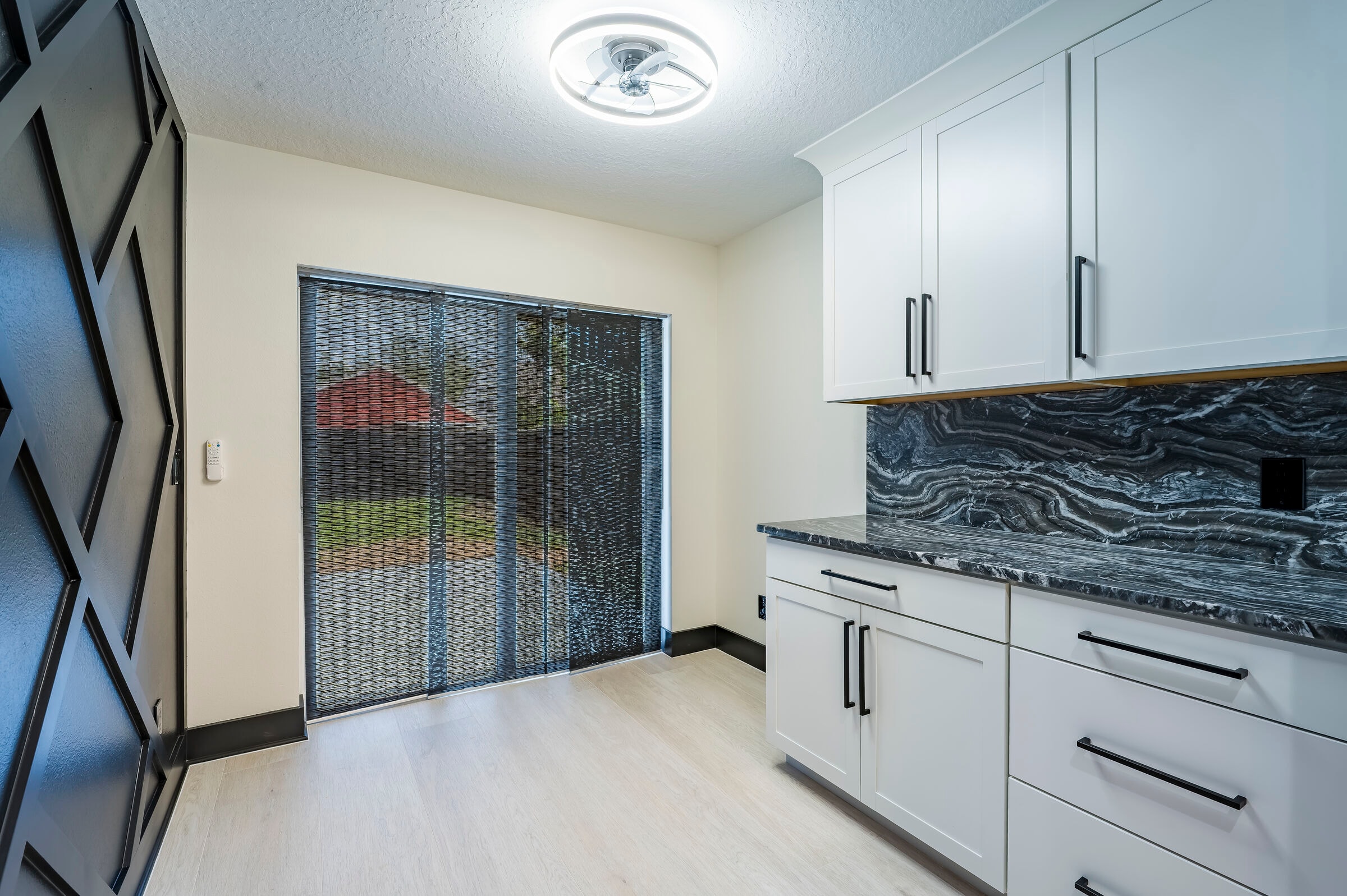Kitchen nook at 7522 Oxford Garden Circle in Apollo Beach Florida — dark marble backsplash, white cabinetry, and sliding glass door with backyard view
