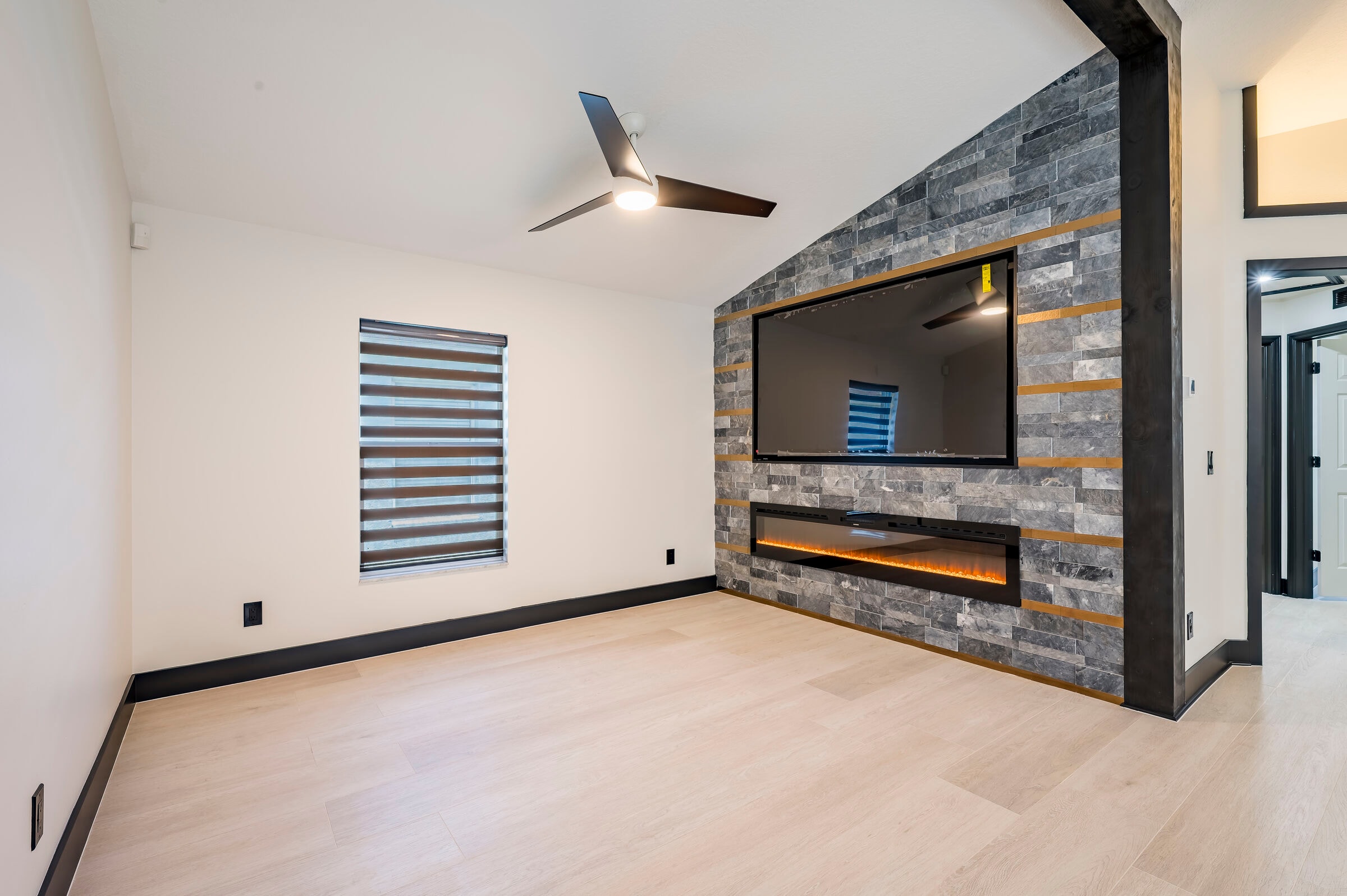 Custom entertainment wall at 7522 Oxford Garden Circle Apollo Beach Florida — stone accent wall with linear electric fireplace and wall-mounted TV