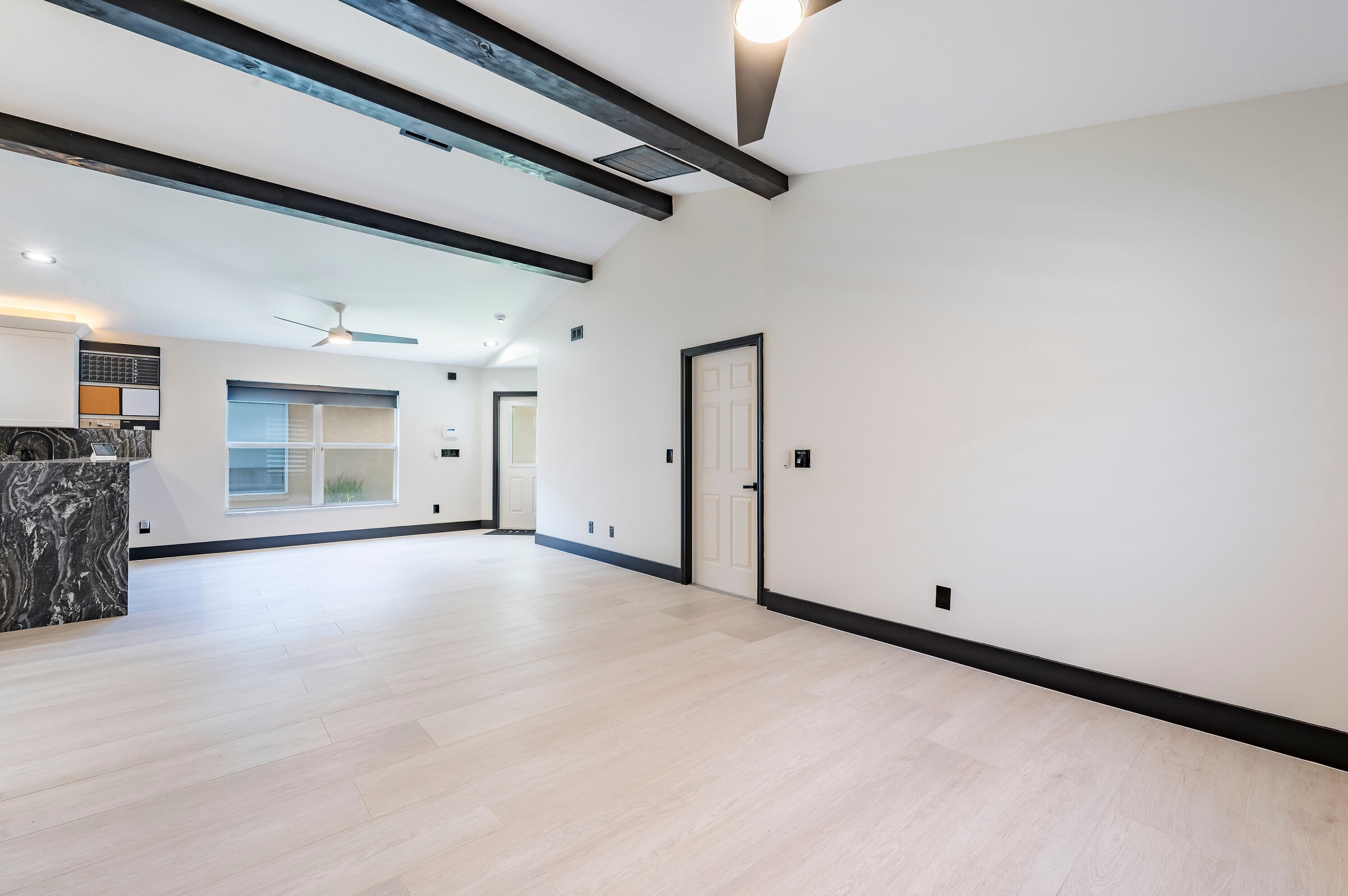 Open living area at 7522 Oxford Garden Circle Apollo Beach — black exposed ceiling beams, marble island edge, and luxury vinyl plank flooring