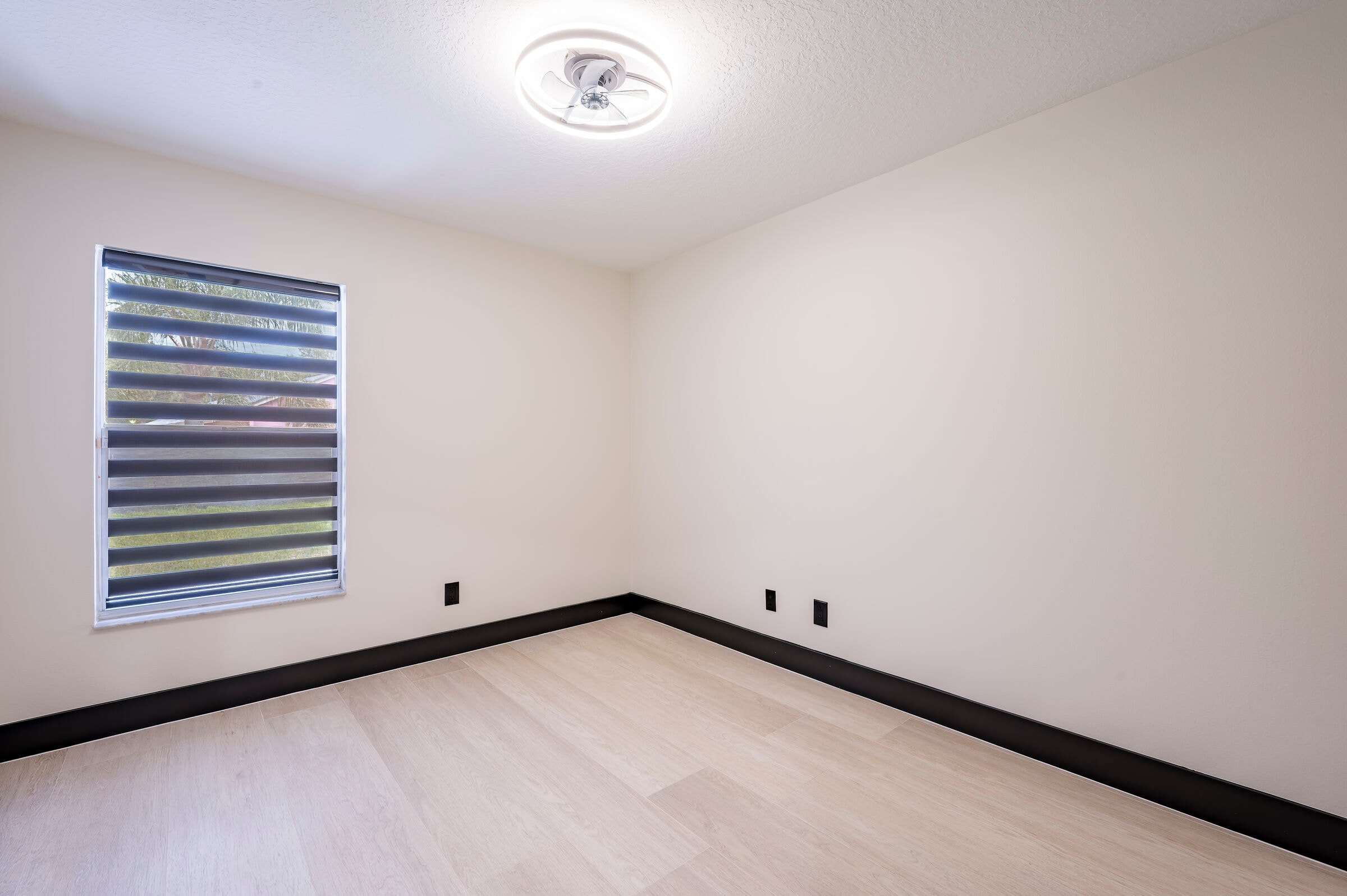 Bedroom at 7522 Oxford Garden Circle in Apollo Beach Florida — ceiling fan, natural light, black baseboard trim, and luxury vinyl plank flooring