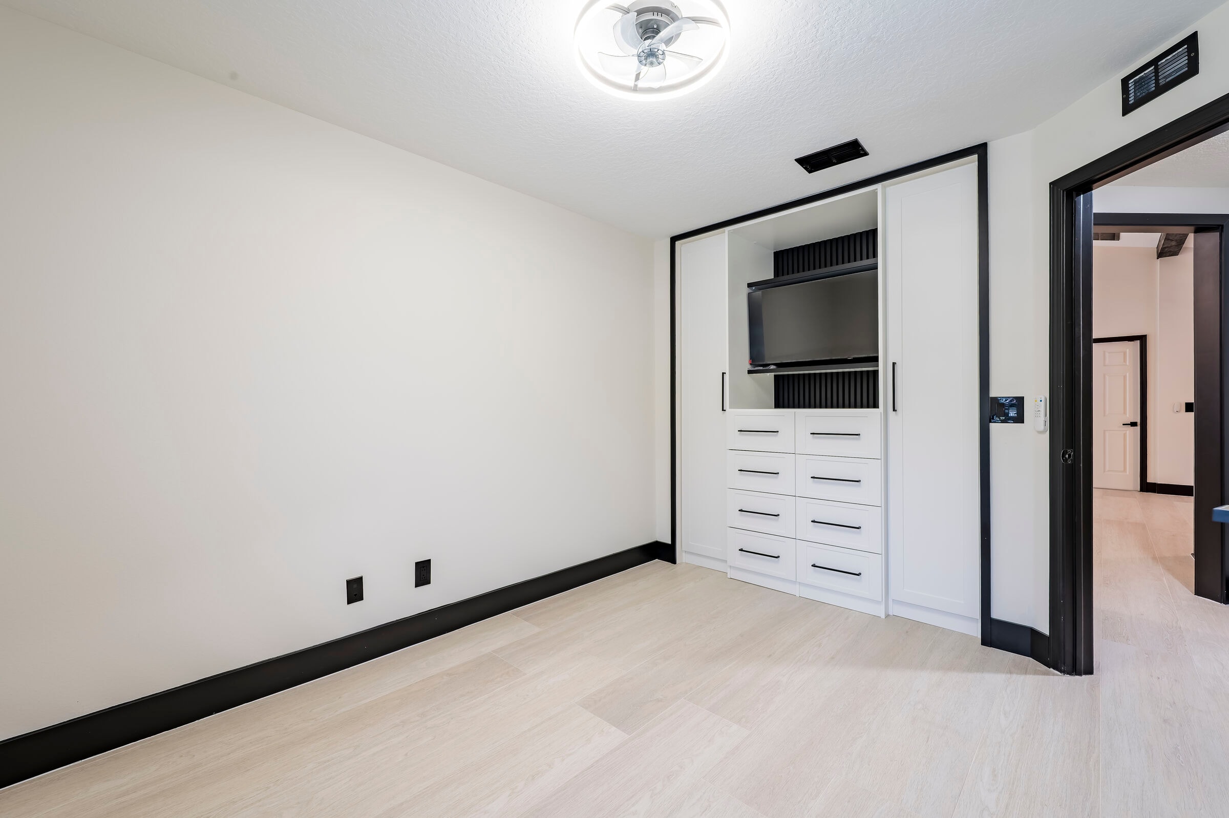 Bedroom with built-in cabinetry at 7522 Oxford Garden Circle Apollo Beach — custom white built-ins with drawers, open media niche, and black trim accents