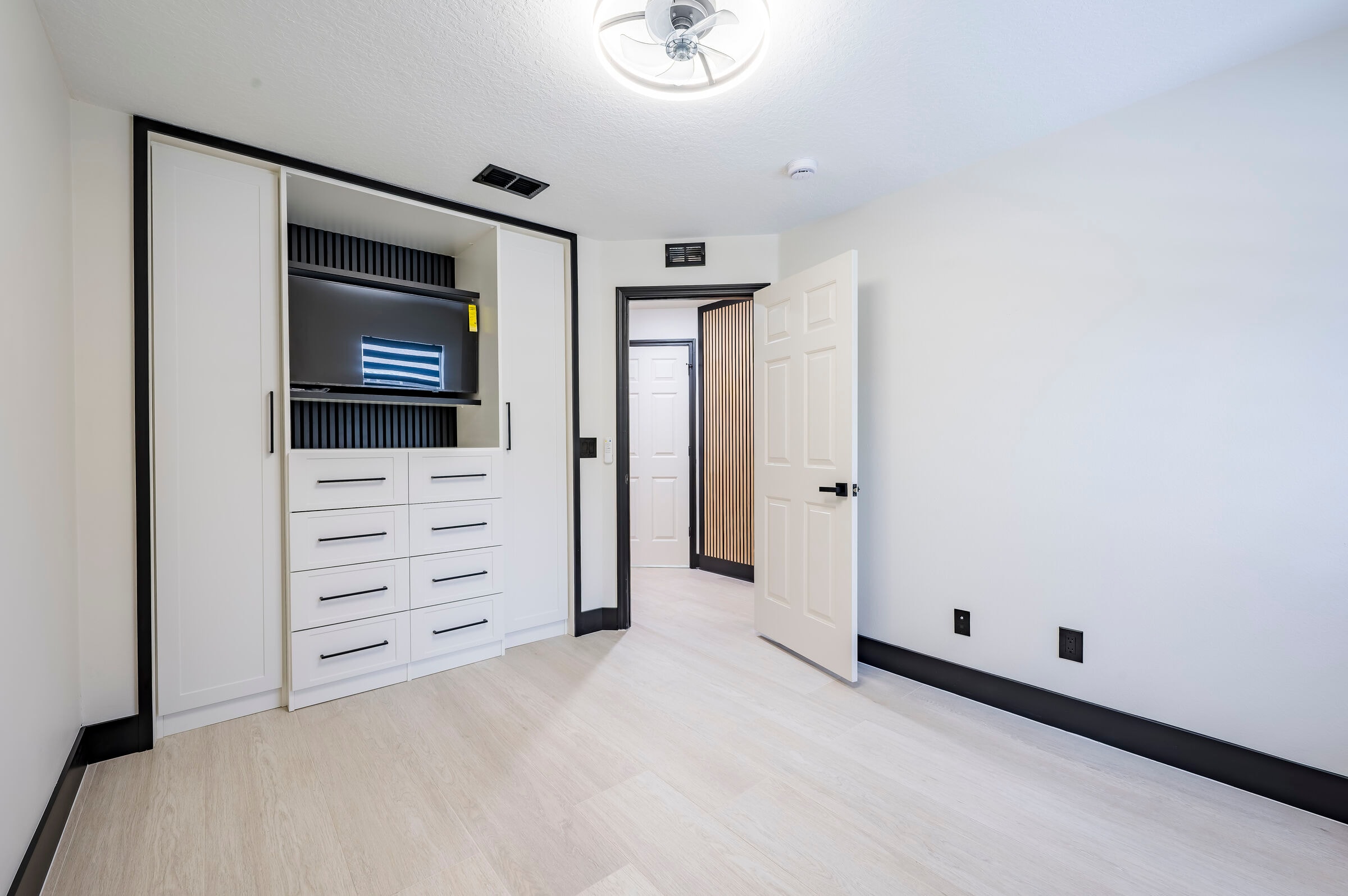Bedroom alternate view at 7522 Oxford Garden Circle in Apollo Beach Florida — custom built-in cabinetry and wood slat barn door to hallway