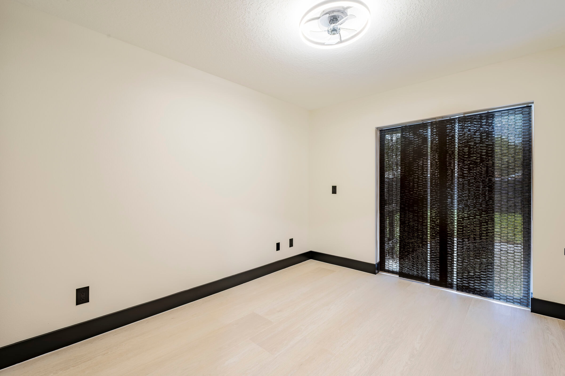 Bedroom at 7522 Oxford Garden Circle Apollo Beach Florida — sliding glass door with black vertical blinds and luxury vinyl plank flooring