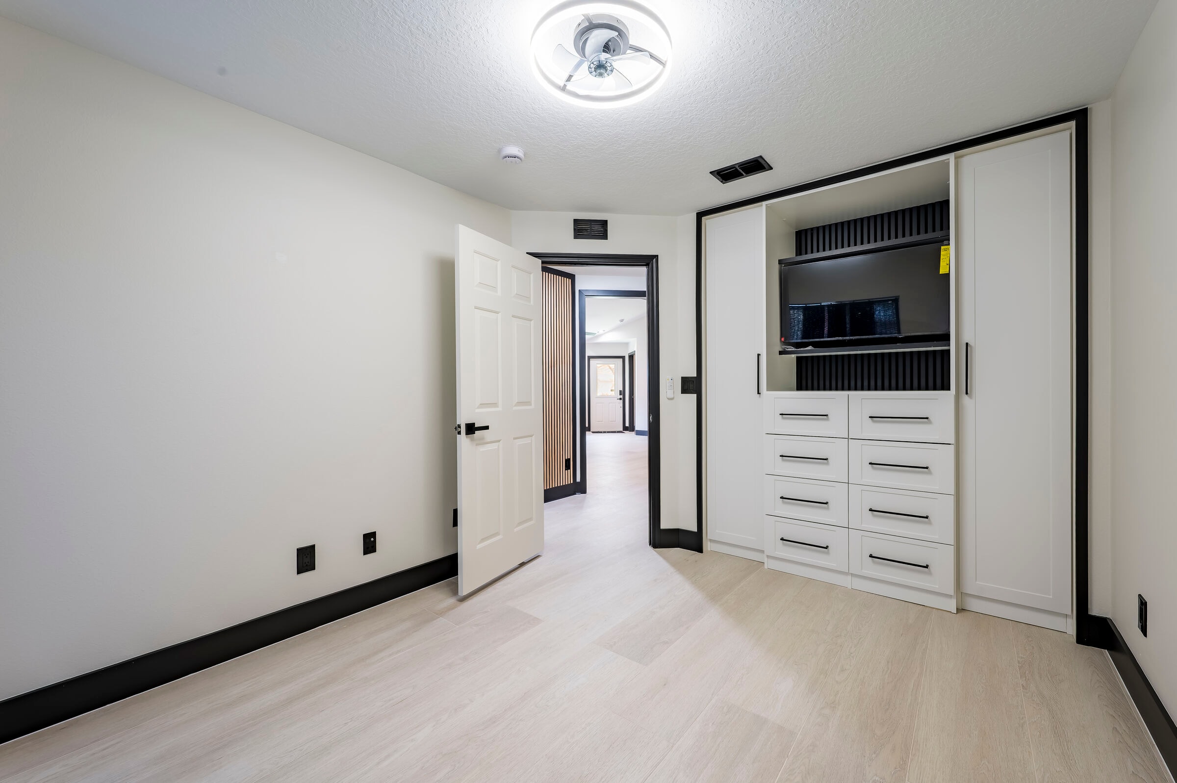 Bedroom with built-in storage at 7522 Oxford Garden Circle Apollo Beach Florida — custom cabinetry and wood slat accent wall visible in hallway