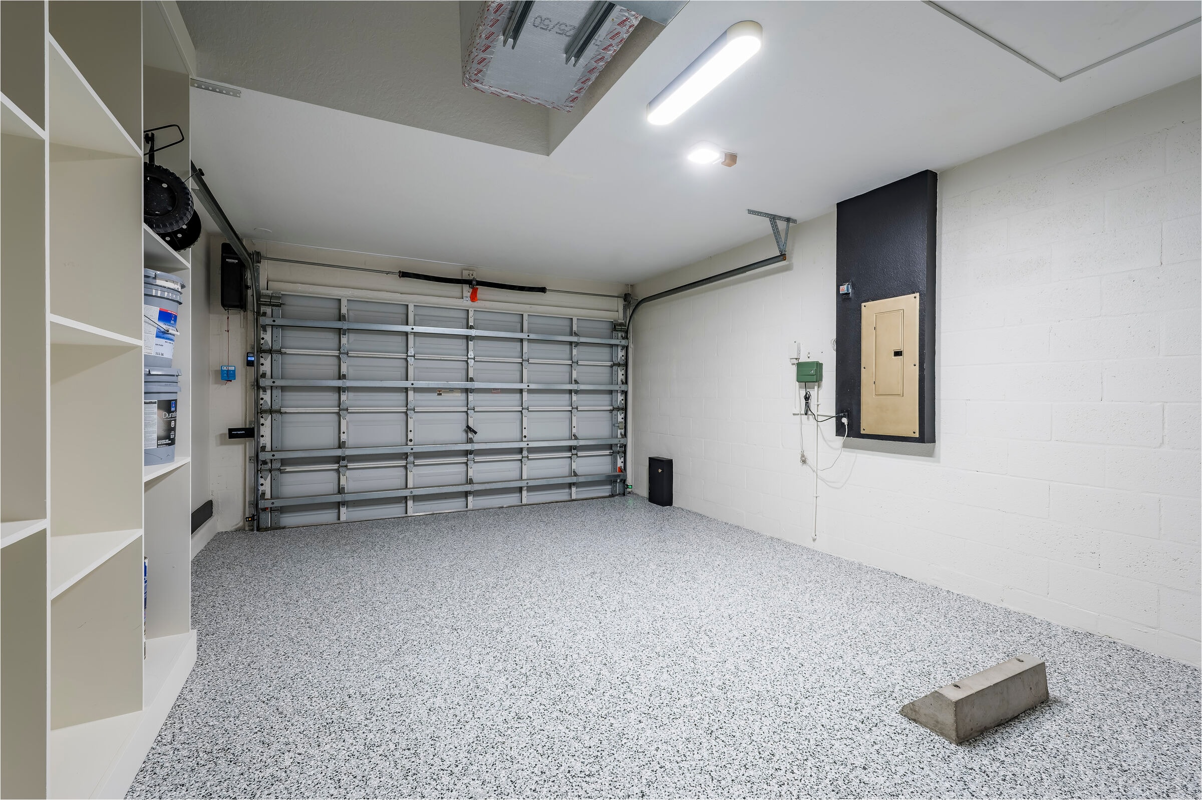 Garage at 7522 Oxford Garden Circle Apollo Beach Florida — custom epoxy flake floor, built-in shelving, electrical panel, and LED lighting